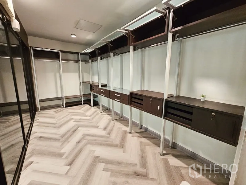 Townhouse for rent in Yan Nawa, Bangkok - Walk-in closet with open shelving, drawers and hanging rails on herringbone floors.
