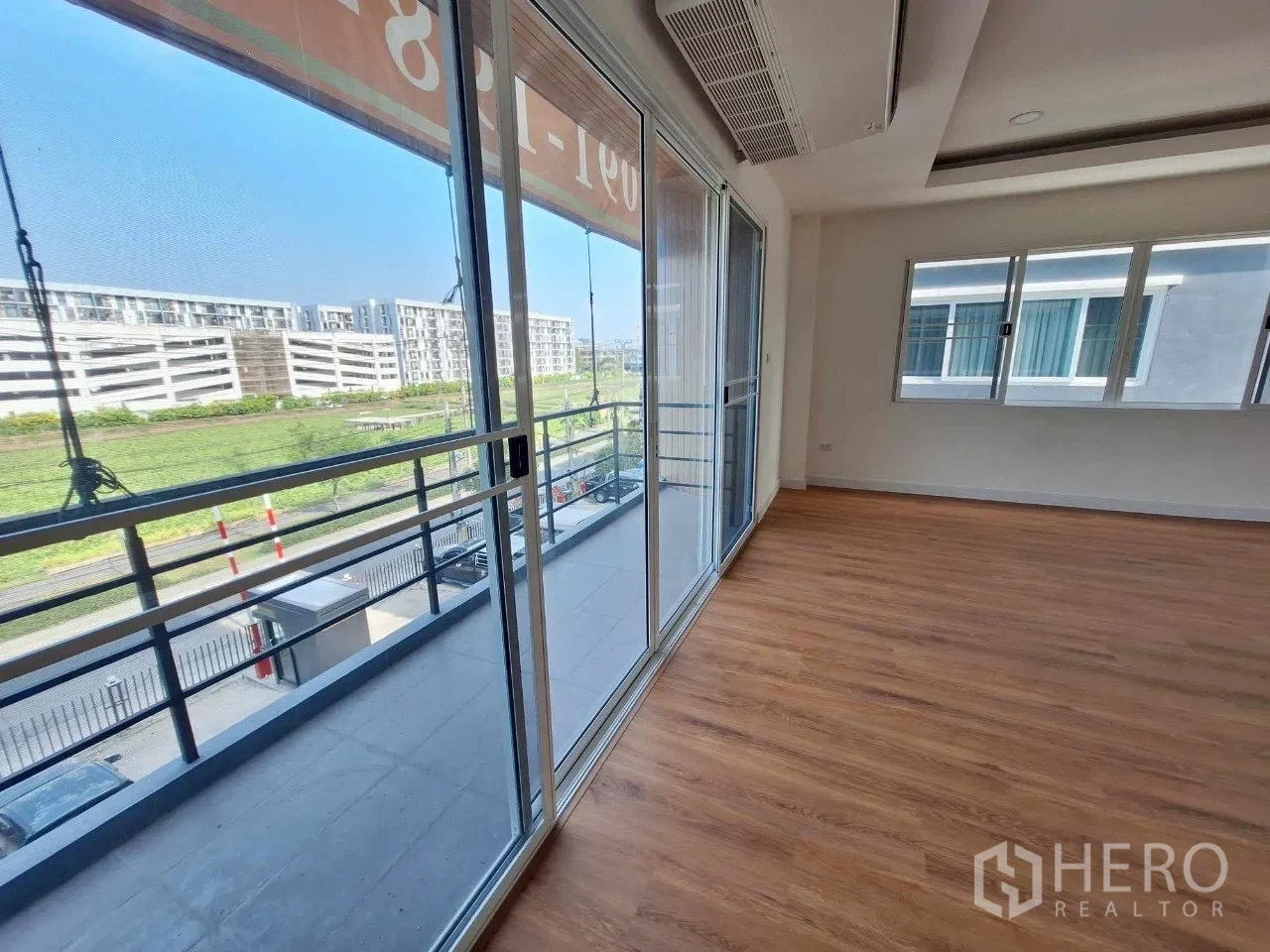 Home Office for sale in Bueng Kum, Bangkok - Corner room opening to a balcony with green views through full-height sliding glass.