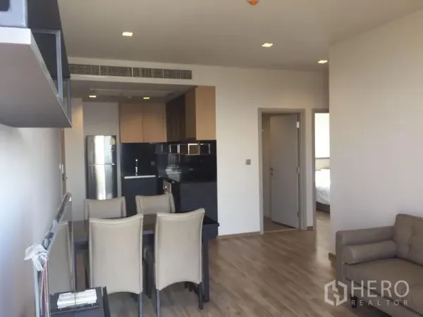Condominium for rent in Chatuchak, Bangkok - Open-plan dining and living area with wood floors leading to the kitchen and bedrooms.