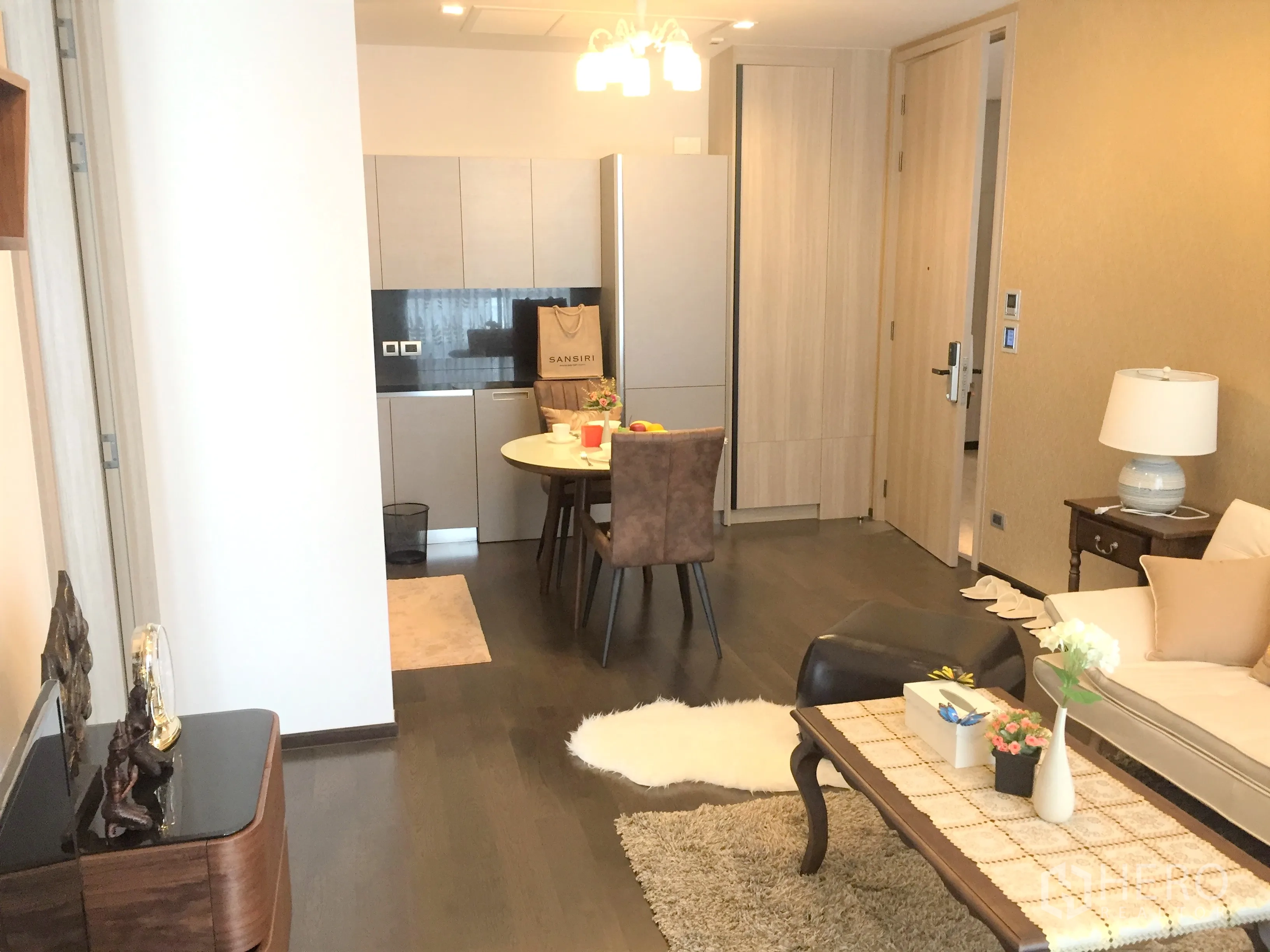 คอนโด ให้เช่าในWatthana, Bangkok - พื้นที่นั่งเล่นแบบเปิดเชื่อมครัวขนาดกะทัดรัด โต๊ะทานอาหารทรงกลม และตู้ลายไม้โทนอ่อน