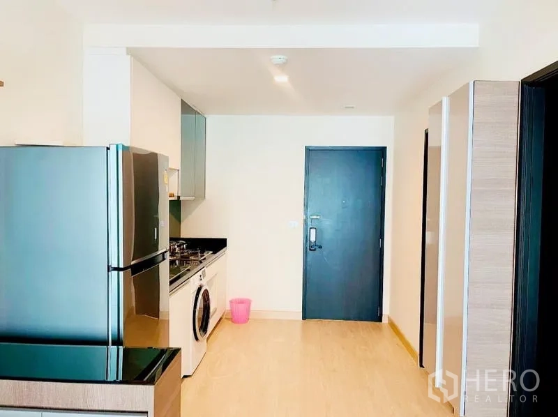 Condominium for rent - Entry corridor with open kitchen, large refrigerator, and dark entry door.