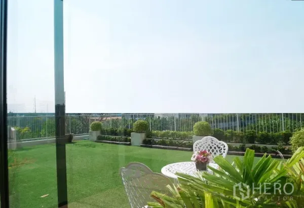 พื้นที่ขายปลีก ให้เช่าในBang Kapi, Bangkok - สวนดาดฟ้าพร้อมราวกันตก พุ่มไม้ตกแต่ง หญ้าเทียม และโต๊ะบิสโทรสีขาว วิวโล่ง