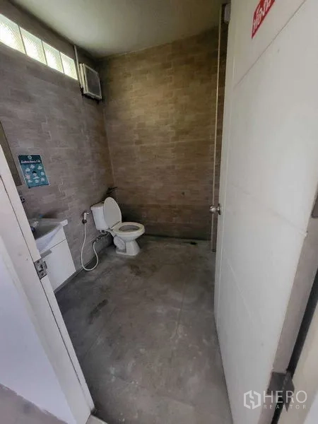店屋 出租在Khlong Toei, Bangkok - 商铺内卫生间，配有马桶、洗手盆与砖纹墙面。