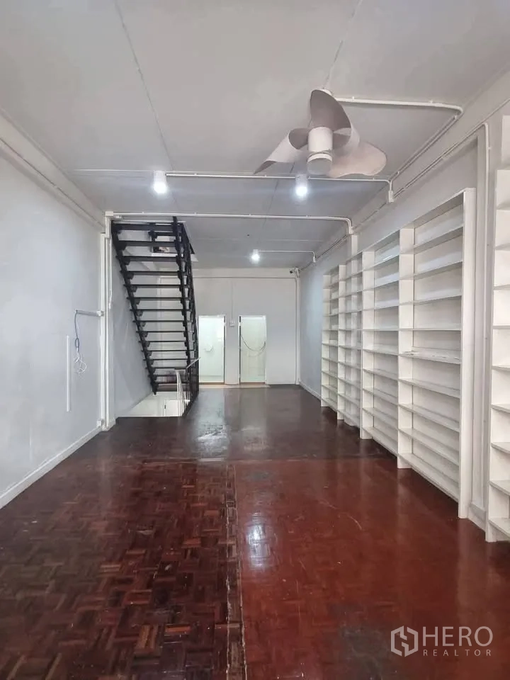 ตึกแถว for rent in Phra Khanong, Bangkok - พื้นที่ชั้นบนพื้นปาร์เกต์สีเข้ม มีบันไดและชั้นวางของติดผนัง.