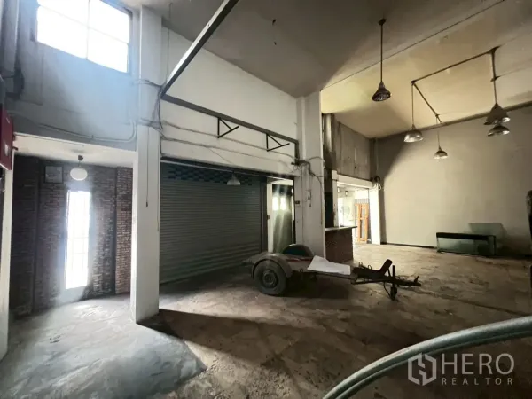 店屋 出租在Phra Khanong, Bangkok - 挑高大厅，带上部采光窗和大型金属卷闸。