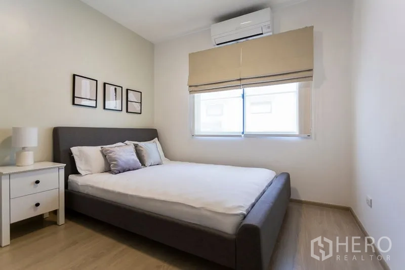 Townhouse for rent in Bang Phli, Samut Prakan - Cozy bedroom with double bed, bedside table, air conditioner and soft neutral tones.