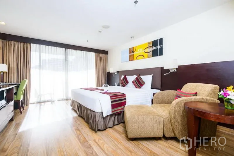 公寓 出租在Khlong Toei, Bangkok - 宽敞卧室，特大床、休闲座椅与落地窗通往阳台