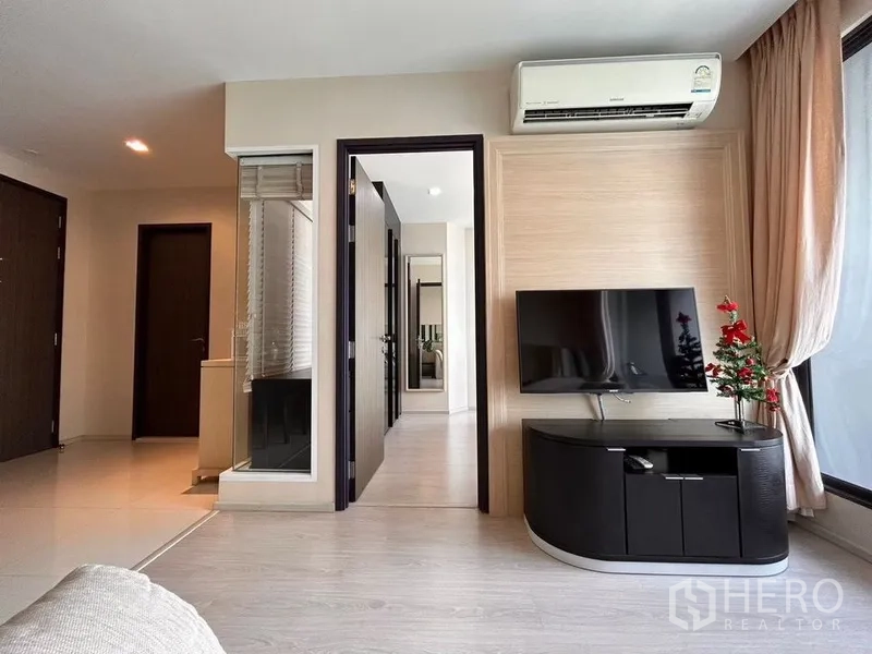 คอนโด ให้เช่าหรือขายในKhlong Toei, Bangkok - ห้องนั่งเล่นพร้อมทีวีติดผนัง เครื่องปรับอากาศ และทางเข้าห้องนอน