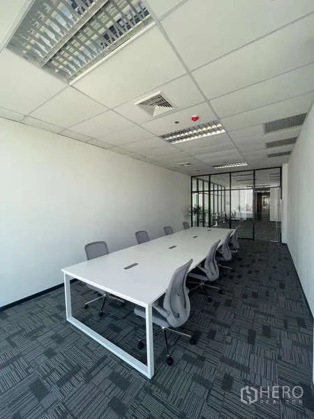 Office Space for rent in Bang Kapi, Bangkok - Bright meeting room with a long white table, gray chairs, carpet tiles, and a glass partition in a modern office.