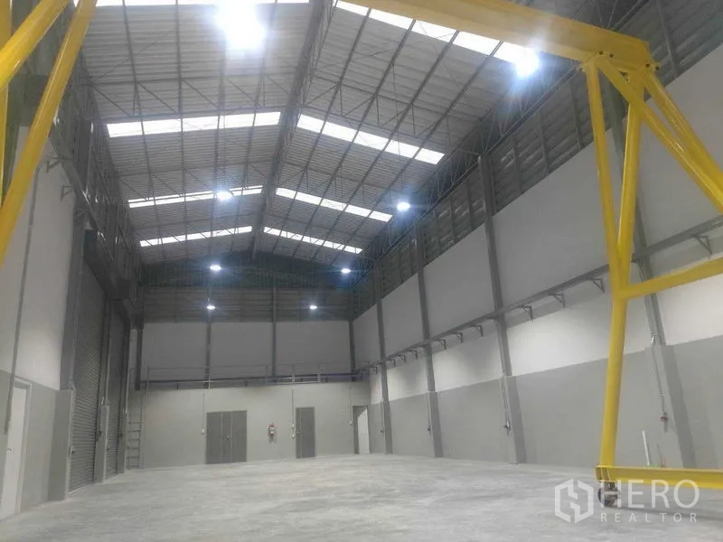 Warehouse for rent in Saphan Sung, Bangkok - Tall interior bay with roller doors, bright lights, and a gantry structure.