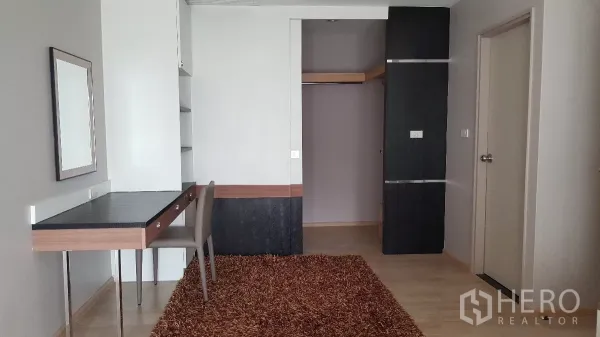 Condominium for rent in Khlong Toei, Bangkok - Study or bedroom with built-in desk, shelving, wardrobe and shag rug flooring.