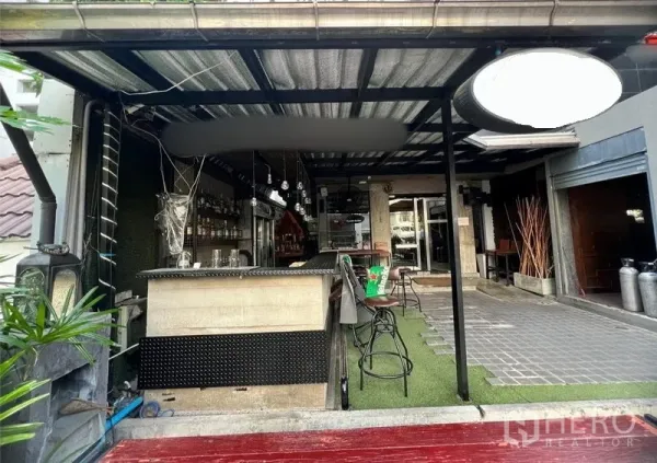 零售空间 出租在Watthana, Bangkok - 临街吧台位于金属顶棚下，配高脚凳与吊灯。