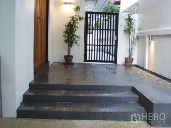 บ้าน ให้เช่าในHuai Khwang, Bangkok - โถงทางเข้ามีบันไดหินสีเข้ม กระถางต้นไม้ ไฟผนัง และประตูรั้วเหล็ก
