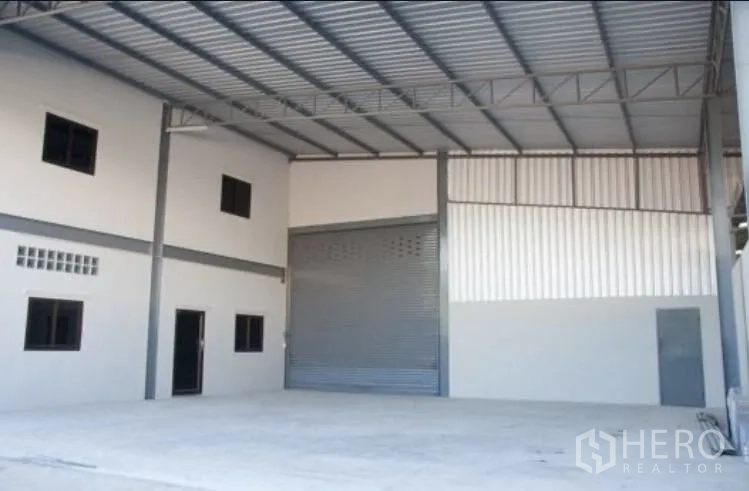 Warehouse for rent in Bang Phli, Samut Prakan - Front loading area with wide roller shutter and office block under roof canopy.
