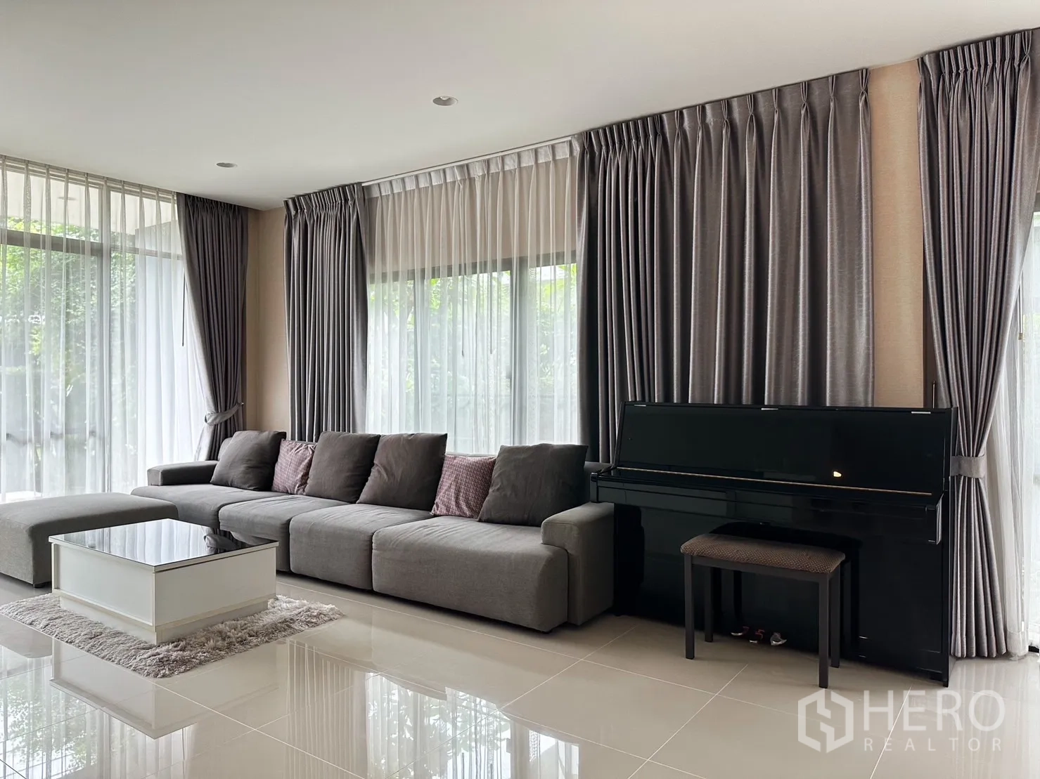 Detached House for rent or sale in Bang Kapi, Bangkok - Living area corner with sofa, black upright piano and large windows.