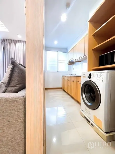 公寓 出租 - 从客厅望向明亮厨房，设洗衣机与置物架。