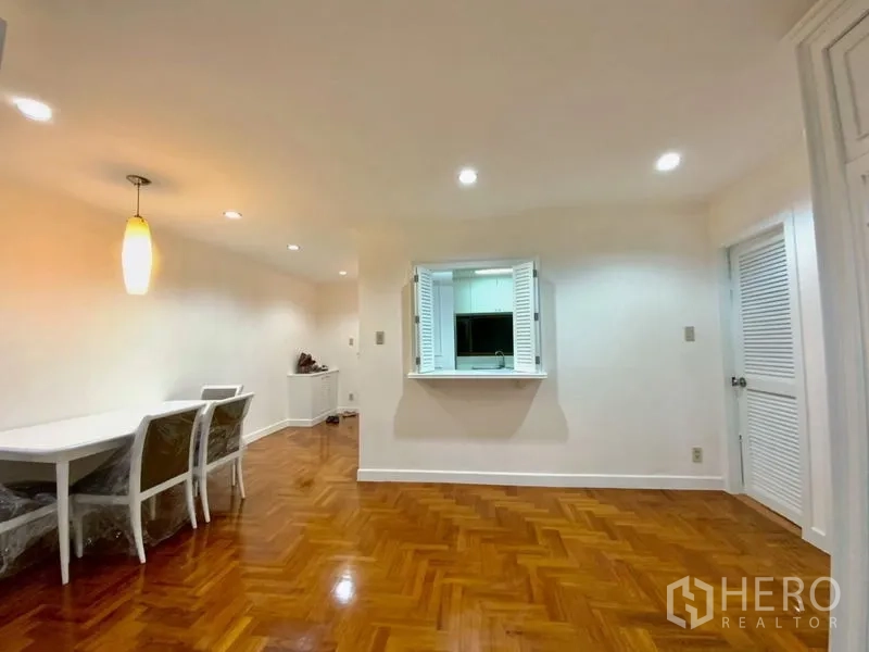 คอนโด ให้เช่าในWatthana, Bangkok - พื้นที่ทานอาหารพร้อมโคมไฟแขวน มีช่องเสิร์ฟอาหารเชื่อมห้องครัว ผนังสีขาวและพื้นไม้ขัดเงา