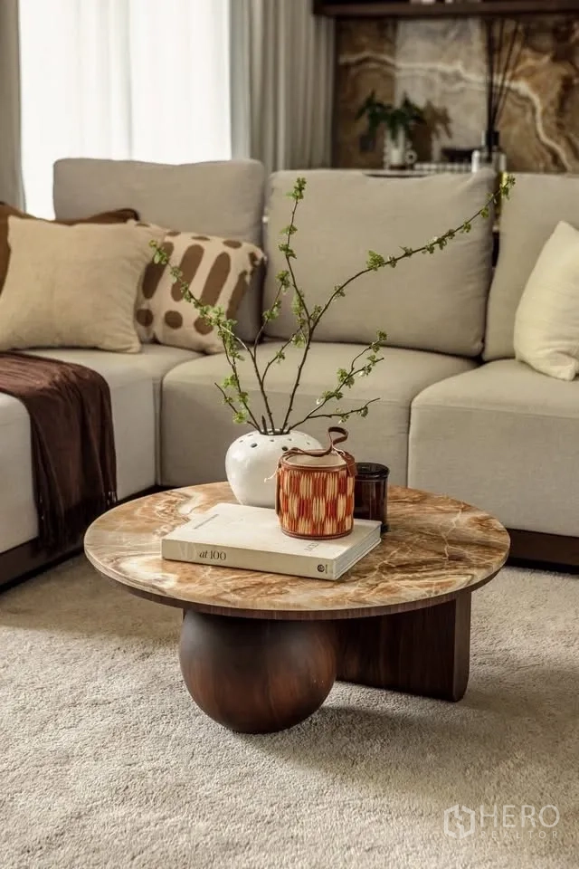 Detached House for rent or sale in Lat Krabang, Bangkok - Round stone coffee table with vases and a book beside a beige sectional on a plush rug.