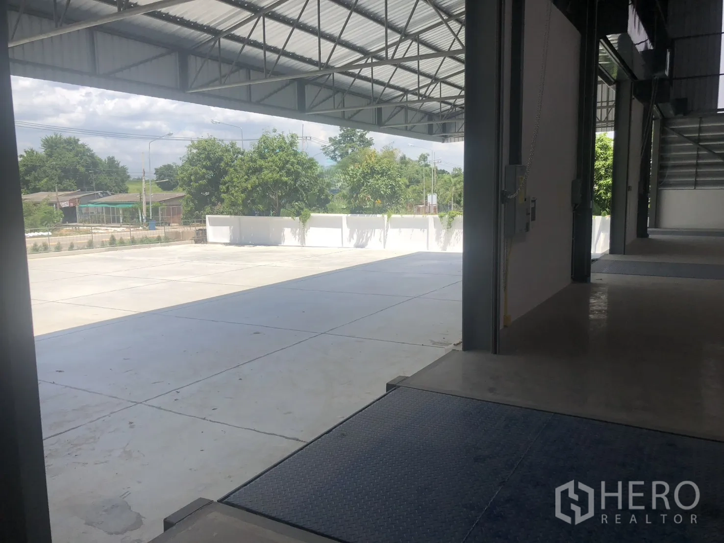 Factory for rent in Si Racha, Chon Buri - Loading bay with dock leveler opening to a wide concrete yard and greenery outside.