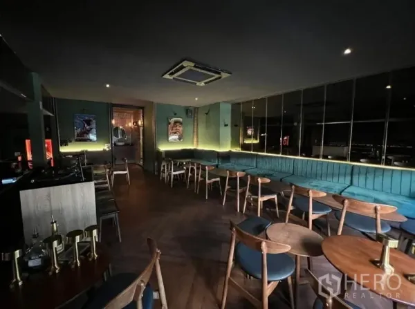 พื้นที่ขายปลีก ให้เช่าในWatthana, Bangkok - โซนเลานจ์พร้อมโซฟายาวสีเขียวอมฟ้า โต๊ะไม้ ผนังกระจก และแอร์ฝังฝ้า