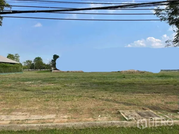 ที่ดิน ขายในBang Phli, Samut Prakan - แปลงที่ดินโล่งระดับเท่ากัน มีหญ้าปกคลุม ติดทางเท้าและถนน มีสายไฟฟ้าเหนือศีรษะ พร้อมทิวต้นไม้และท้องฟ้าใส