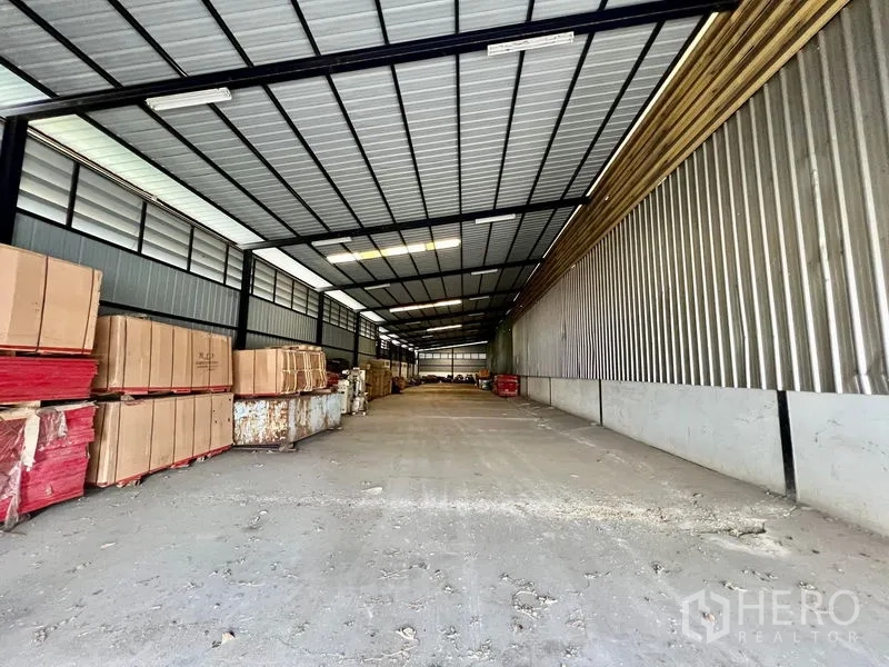 Warehouse for rent in Phra Samut Chedi, Samut Prakan - Covered storage aisle with stacked pallets and cartons inside the warehouse.