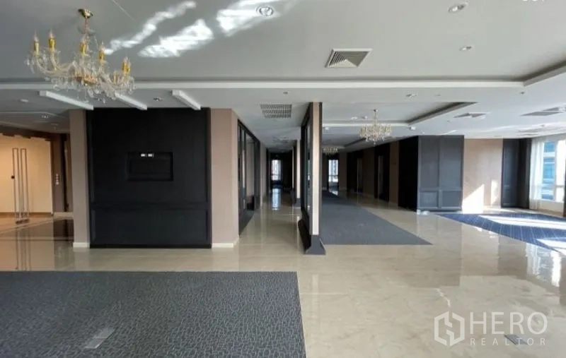 Office Space for rent - Long office hall with chandeliers, gray panels, carpet insets and abundant natural light.