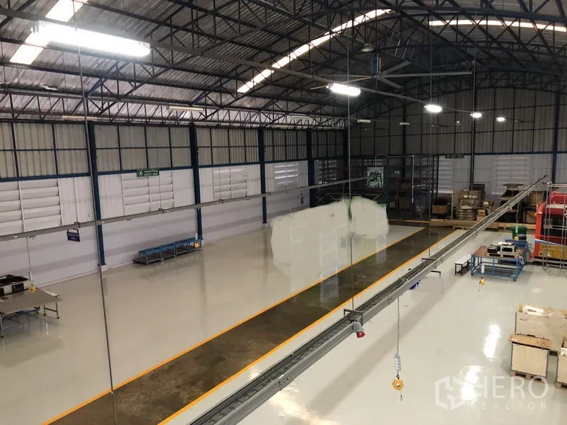 Factory for sale in Pathum Thani - High‑ceiling factory floor with steel trusses and glossy epoxy flooring.
