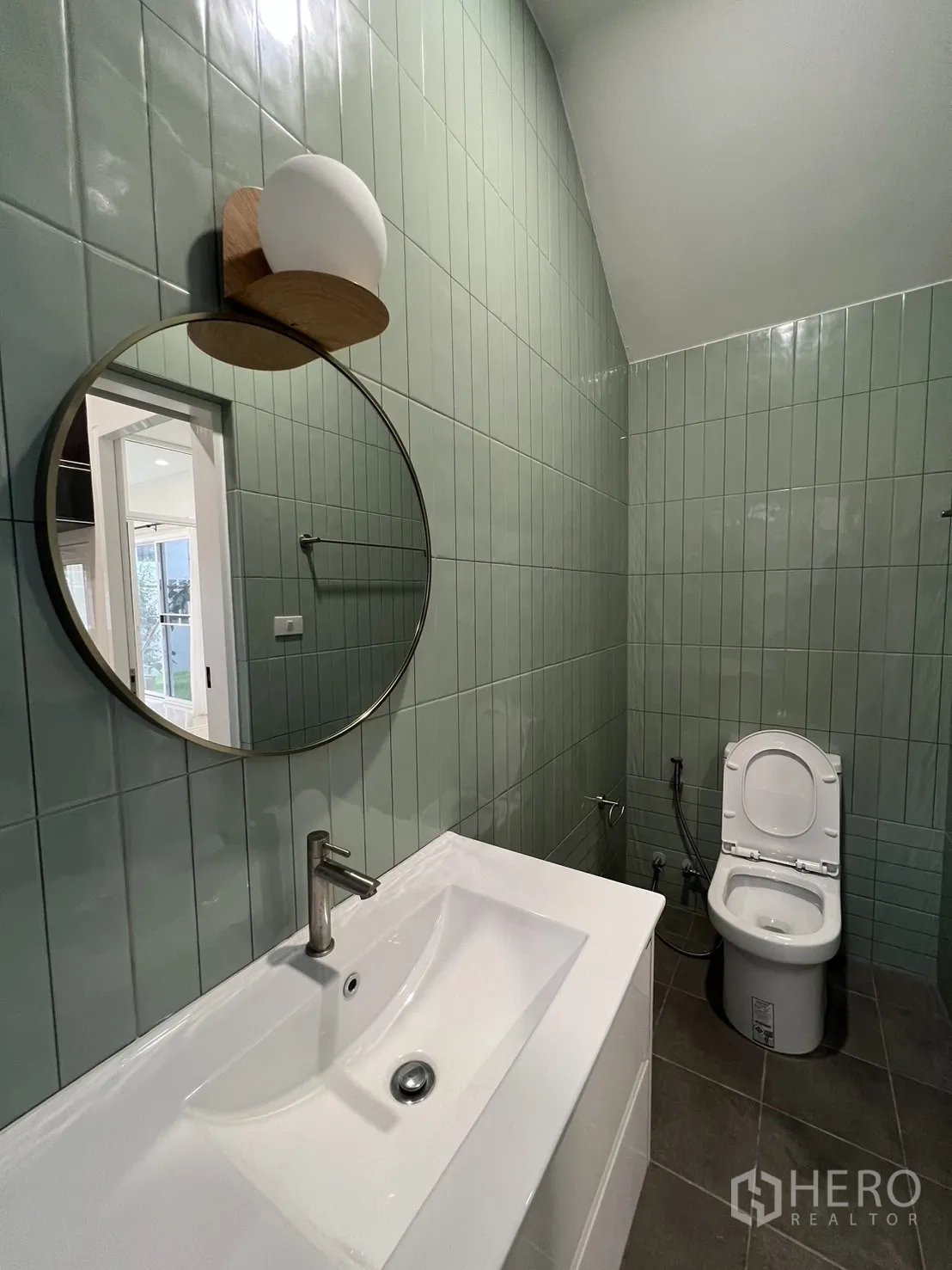 Detached House for rent in Saphan Sung, Bangkok - Powder room featuring green vertical tiles, round mirror and vanity.