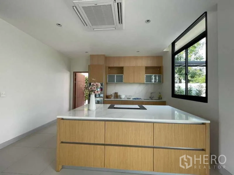 บ้าน ขายในKhlong Sam Wa, Bangkok - ครัวสมัยใหม่พร้อมไอส์แลนด์ขนาดใหญ่ ตู้ลายไม้ เตาอินดักชัน และหน้าต่างมองสวน