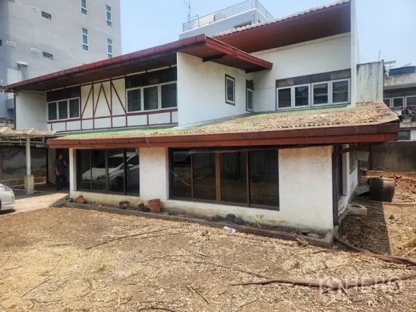 Detached House for rent in Watthana, Bangkok - Rear exterior of the two-storey house with carport and a large open yard.