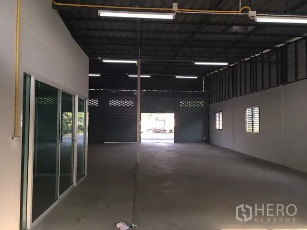 คลังสินค้า ให้เช่าในLam Luk Ka, Pathum Thani - ภายในโกดังแบบโอเพ่นสเปซ หลังคาโครงเหล็กสูง ไฟสว่าง พื้นคอนกรีต และทางออกประตูม้วนด้านหลัง.