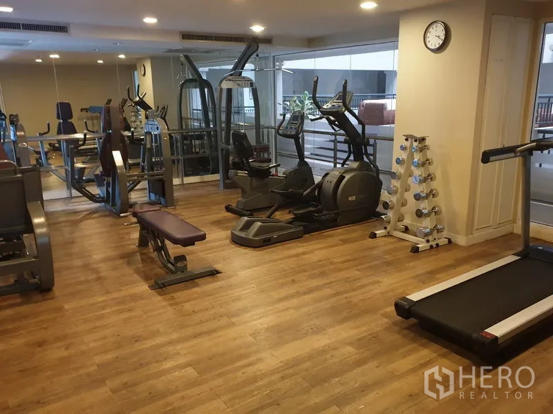 Condominium for rent in Watthana, Bangkok - Fully equipped fitness room with treadmills, ellipticals, weights, and mirrors.