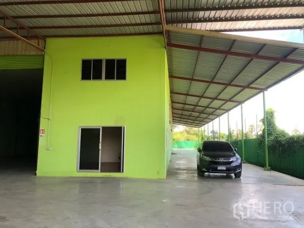 Factory for rent in Sam Khok, Pathum Thani - Two-storey internal office block with sliding glass door and covered parking/loading space.