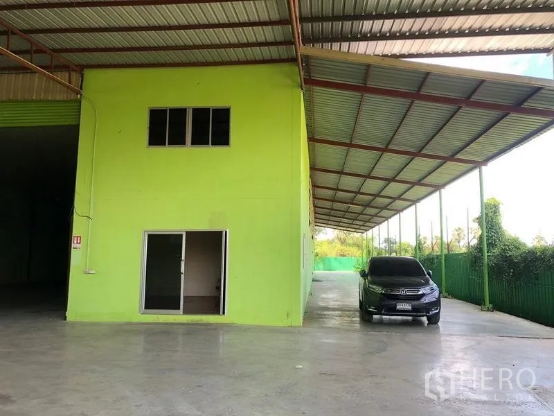 Factory for rent in Sam Khok, Pathum Thani - Two-storey internal office block with sliding glass door and covered parking/loading space.