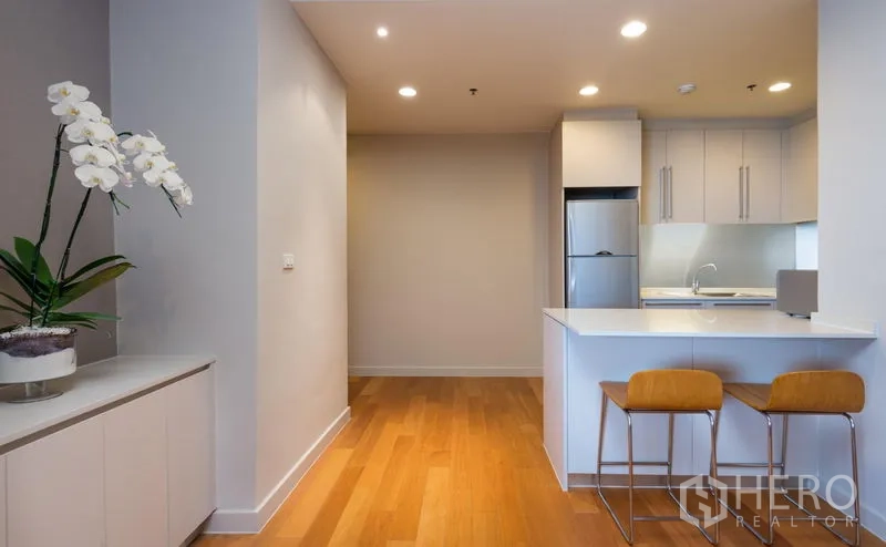 Condominium for rent in Bang Kho Laem, Bangkok - Kitchen entry with quartz peninsula, bar stools, recessed lighting and fridge.