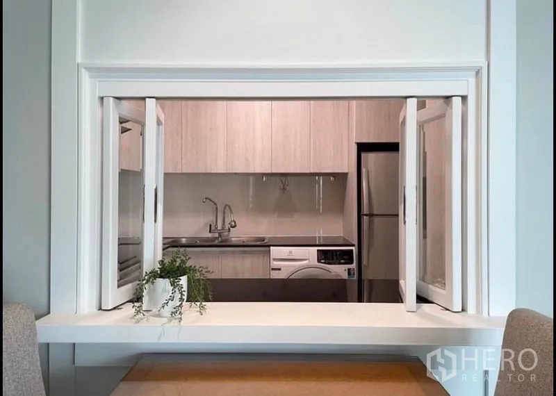 公寓 出租在Sathon, Bangkok - 厨房与餐区相连的传菜窗，可见水槽和洗衣机。