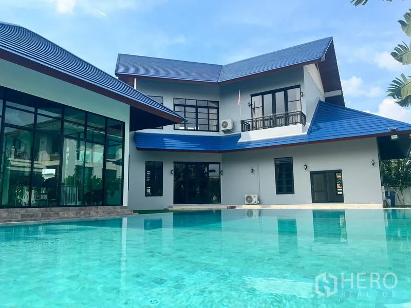 Detached House for sale in Prawet, Bangkok - Exterior view of contemporary two-storey home with blue tiled roof by the pool.