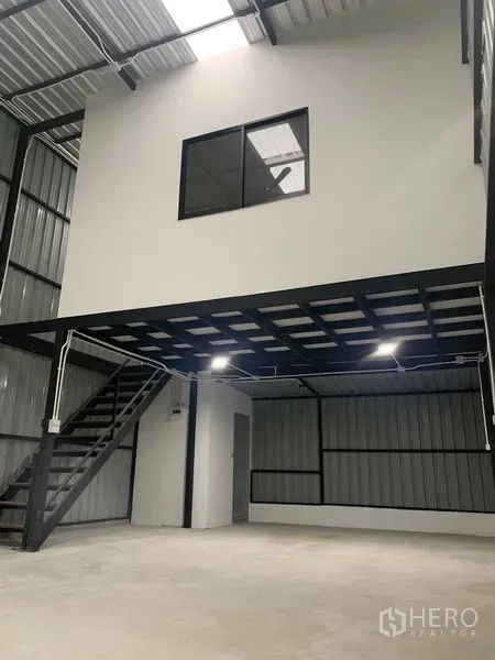 Warehouse for rent in Bangkok - Open warehouse floor featuring a steel mezzanine office, staircase, and bright LED lighting.