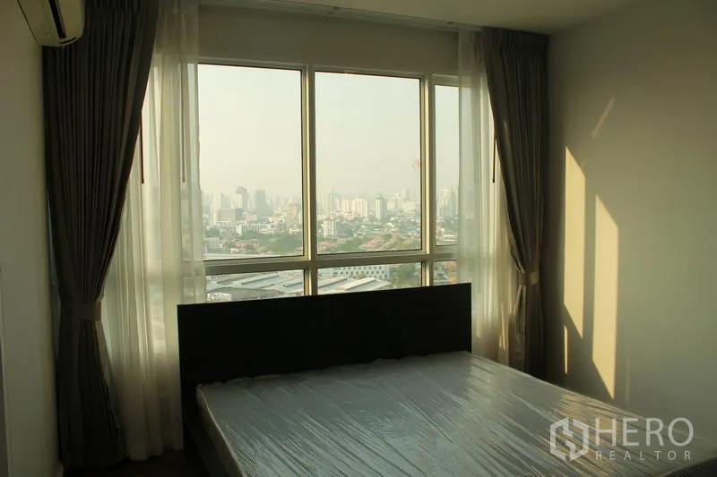 Condominium for rent or sale in Watthana, Bangkok - Master bedroom with floor-to-ceiling windows offering a wide city view.