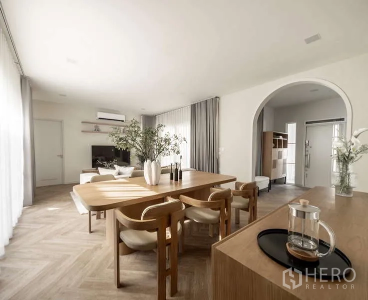 Detached House for rent or sale in Bang Phli, Samut Prakan - Open-plan dining area with wooden table and arched doorway next to living room.