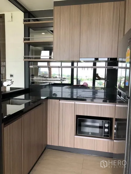 คอนโด ให้เช่าในWatthana, Bangkok - ครัวรูปตัวแอลขนาดกะทัดรัด เคาน์เตอร์หินสีดำ ไมโครเวฟบิวท์อิน อ่างล้างจาน และตู้เก็บของ