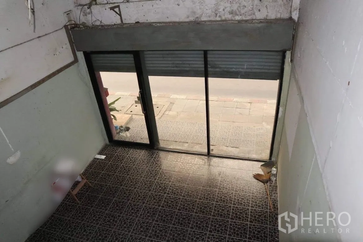 Shophouse for sale in Huai Khwang, Bangkok - Street-facing glass storefront with sliding doors and roller shutter at the entrance.
