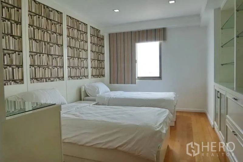 Condominium for rent in Watthana, Bangkok - Guest bedroom with two single beds and a bookshelf-pattern feature wall.