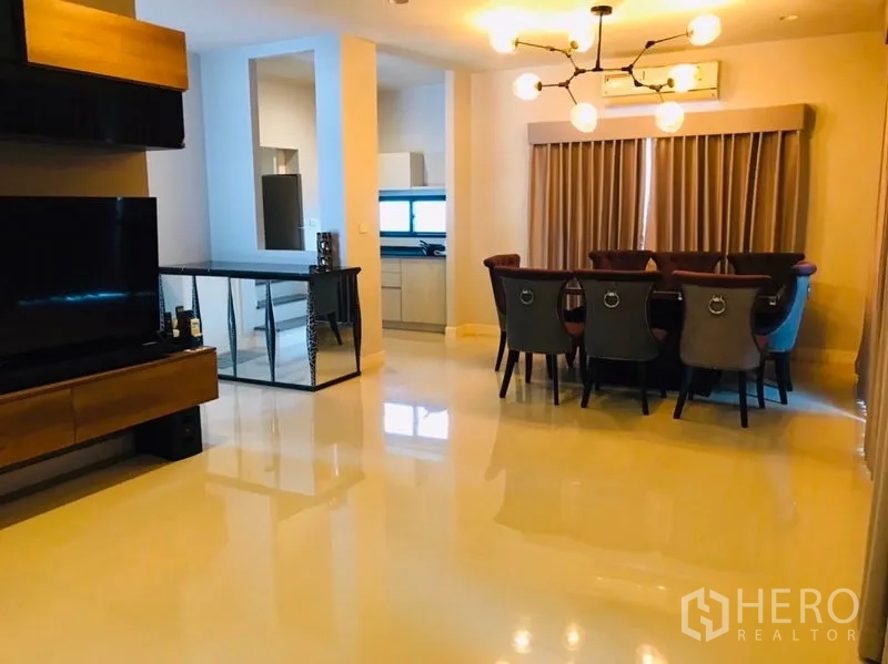 独立式住宅 出租或出售在Pathum Thani - 客餐厅一体空间，吊灯与开放视线到厨房