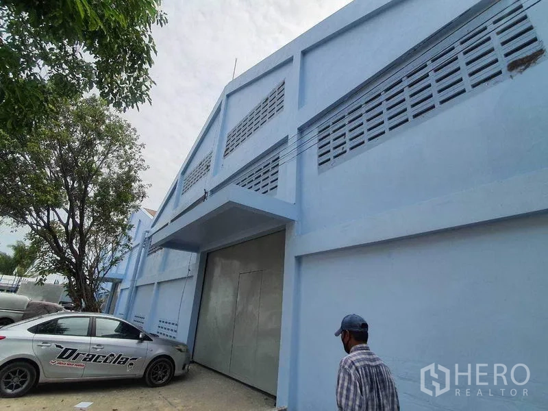 货栈 出租在Nakhon Pathom - 蓝色仓库外立面斜角视图，配大型金属推拉门和停车区。