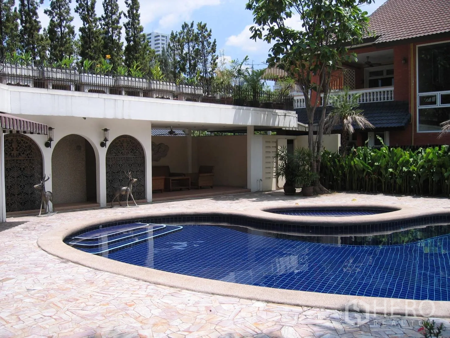 บ้าน ให้เช่าในWatthana, Bangkok - สระว่ายน้ำทรงโค้งพร้อมสปายกระดับ ข้างระเบียงพักผ่อนแบบมีชายคาและต้นไม้ร่มรื่น