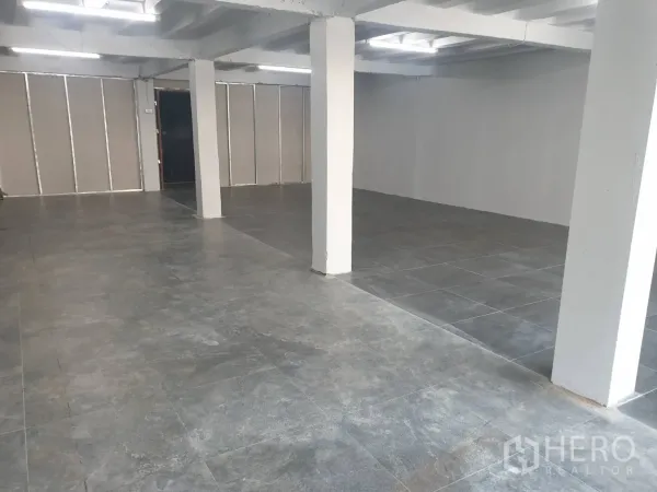 零售空间 出租在Khlong Toei, Bangkok - 开放式零售室内，灰色瓷砖地面、白色承重柱与明亮长条灯。