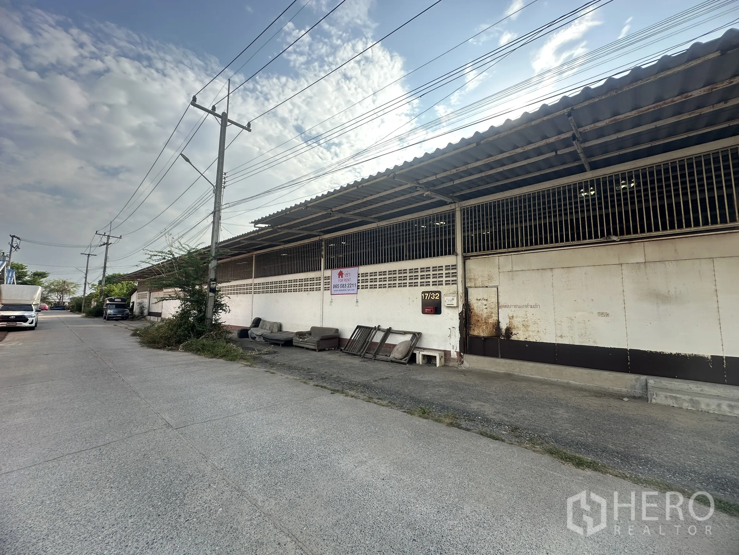 Warehouse for rent in Lam Luk Ka, Pathum Thani - Exterior of the warehouse showing sliding metal doors along the road.