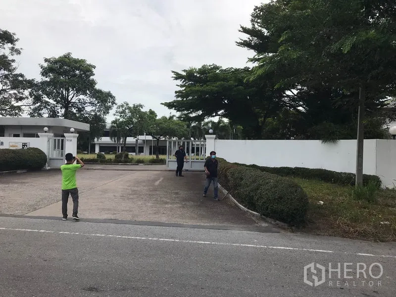 โรงงาน ให้เช่าในMueang Chon Buri, Chon Buri - ทางเข้าโรงงานมีกำแพงและประตูรั้วกว้าง พร้อมป้อมยามและต้นไม้จัดสวน